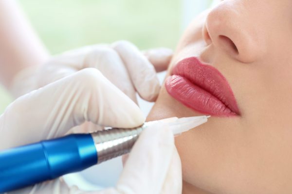 Young woman having permanent makeup on lips in beautician salon Young woman having permanent makeup on lips in beautician salon