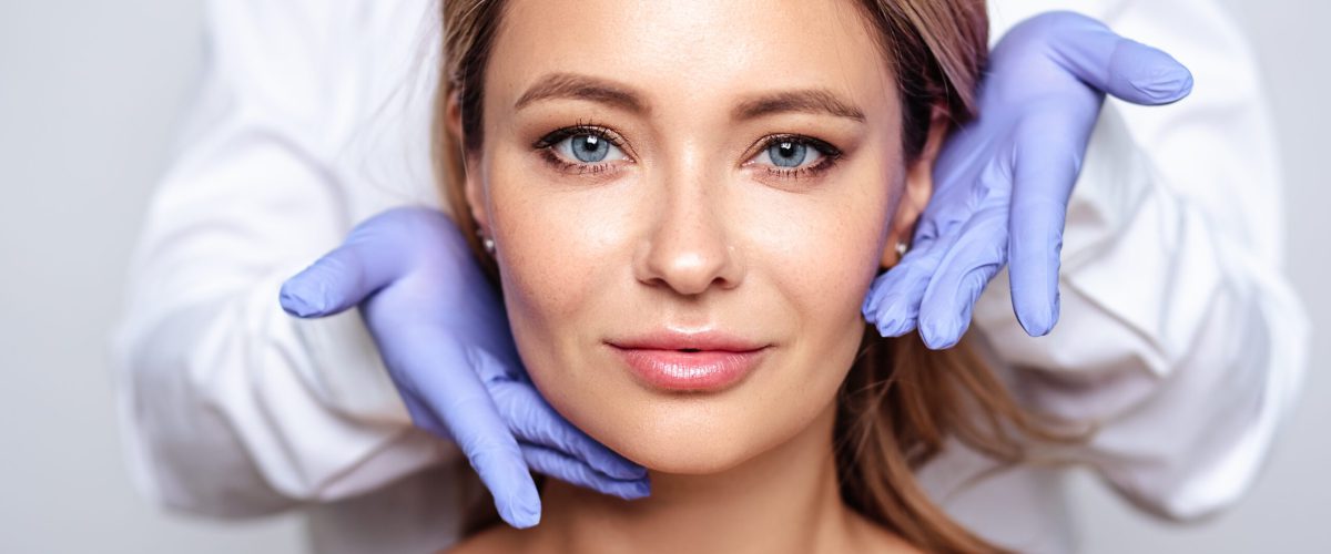 Close up portrait of young blonde woman with cosmetologyst hands